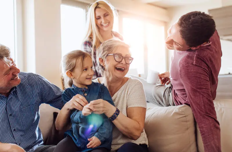 family sitting with grandma on the couch smiling