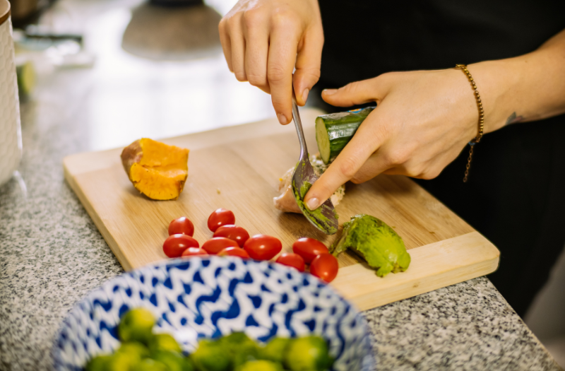 Close up of an Age in Place care giver cutting vegetables while preparing a meal