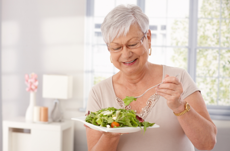 Age in Place client smiling while eating a plate of salad