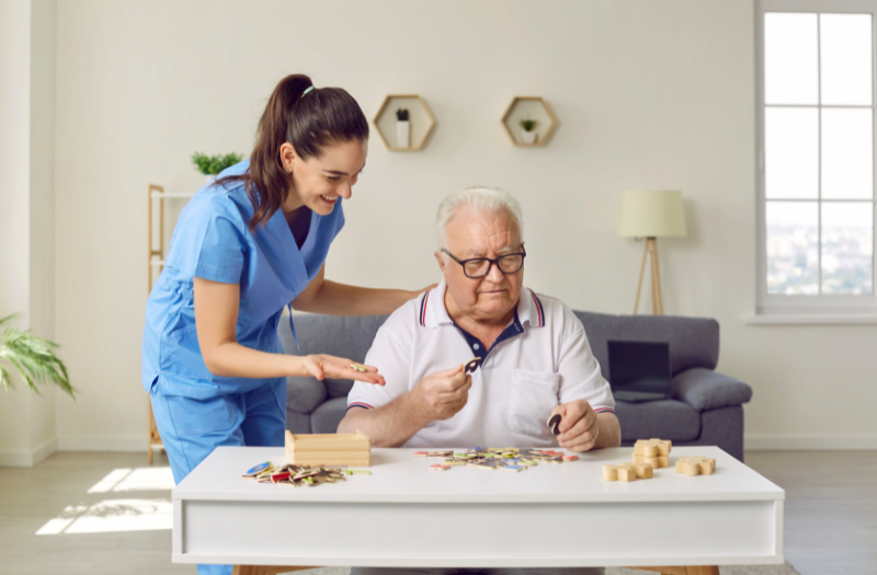 Compassionate caregiver assisting senior with puzzle, promoting companionship and engagement at home in Wilmington, NC.