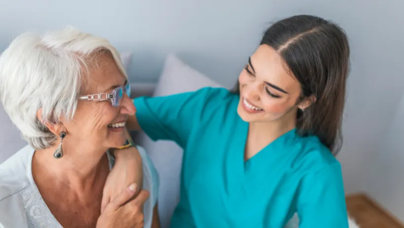 an Age in Place client and her caregiver smiling at each other and holding hands